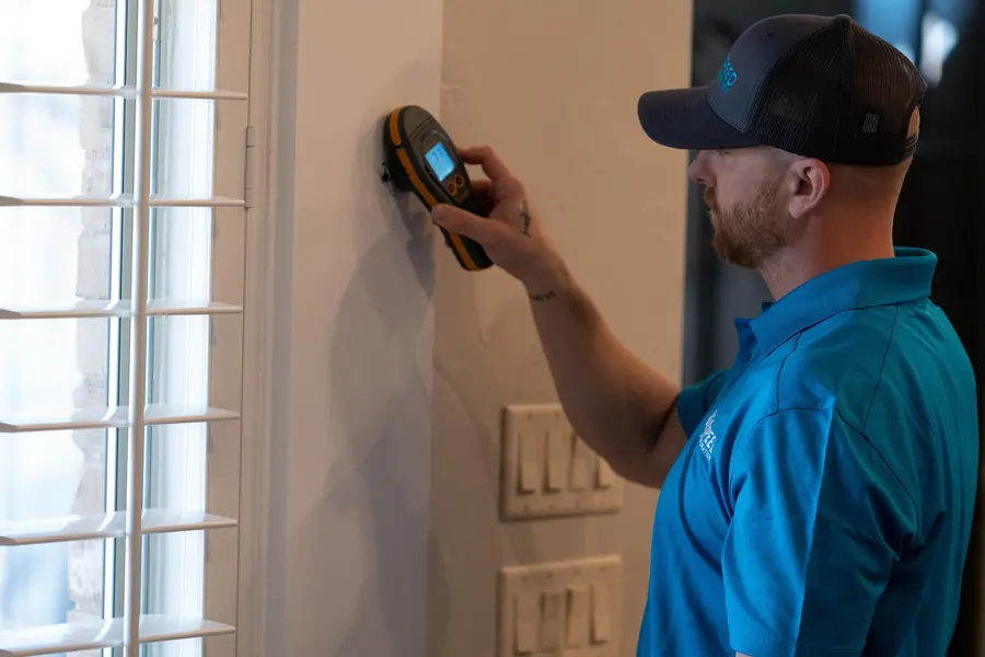 Technician checking a wall with a pinless moisture meter during a Fresh Meadows walkthrough