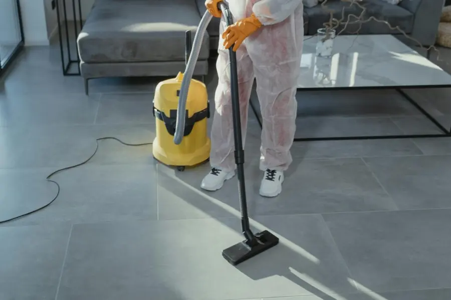 Tech in a protective suit and gloves extracting contaminated water from a Fresh Meadows floor