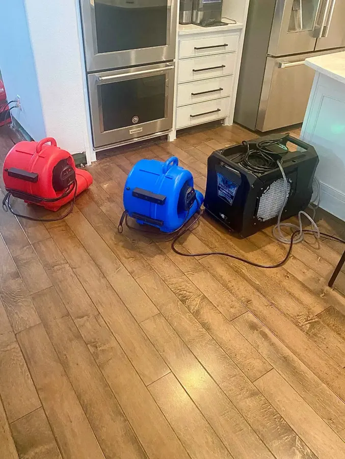 Air movers and a dehumidifier drying a kitchen wood floor in Fresh Meadows